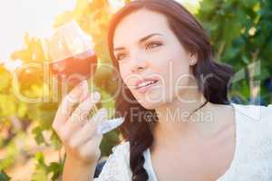 Beautiful Young Adult Woman Inspects Glass of Wine in The Vineyard