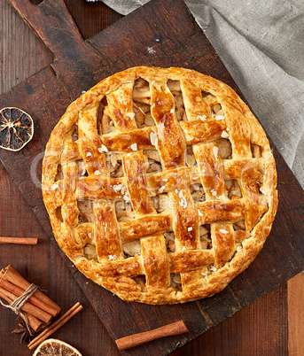 baked whole round apple pie on a brown wooden board