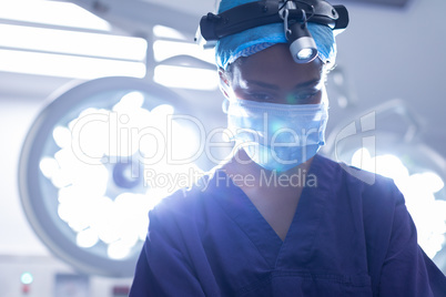 Female with surgical headlight performing operation in operation theater at hospital