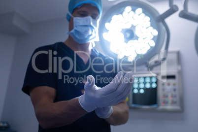 Male surgeon wearing surgical gloves in operation theater