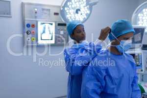 Female surgeon helping male surgeon to wear surgical mask in operation theater