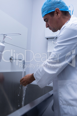 Male surgeon washing hands in sink at hospital