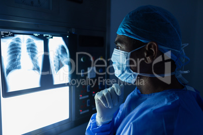 Male surgeon reading x ray in operating room at hospital