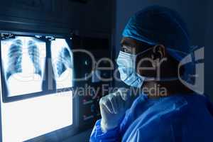 Male surgeon reading x ray in operating room at hospital