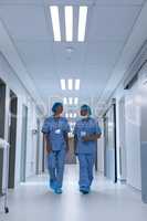 Surgeons talking with each other while walking in the corridor at hospital