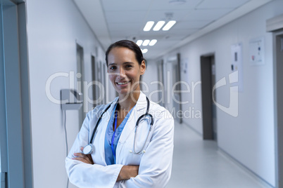 Female doctor with arms crossed looking at camera in the corridor at hospital