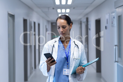 Female doctor using mobile phone in the corridor at hospital