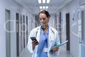 Female doctor using mobile phone in the corridor at hospital