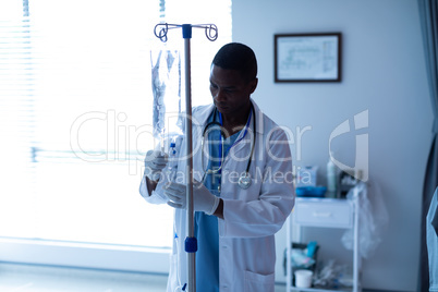 Male doctor checking intravenous therapy drip in the ward