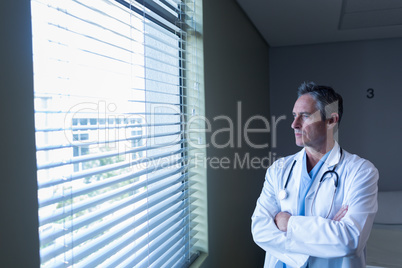 Mature male doctor looking through window in the hospital