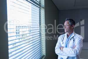 Mature male doctor looking through window in the hospital