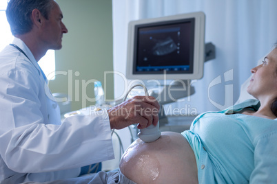 Doctor doing ultrasound scan for pregnant woman in hospital