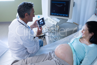 Male doctor doing ultrasound scan for pregnant woman in hospital