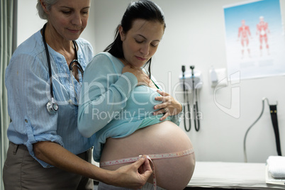 Female doctor measuring pregnant woman belly
