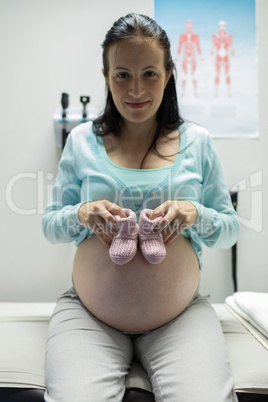 Pregnant woman holding baby shoes in hospital