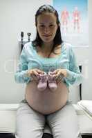 Pregnant woman holding baby shoes in hospital