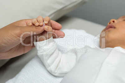 Baby holding female doctors finger in hospital