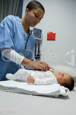 Doctor examining baby with stethoscope in medical examination room