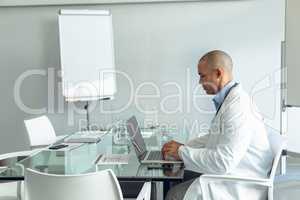 Male doctor using laptop at table in the hospital