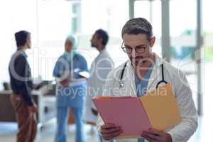 Male doctor looking at medical file in hospital