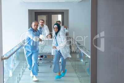 Doctor pushing emergency stretcher bed in corridor at hospital