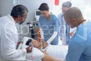 Doctors using defibrillator on patient in ward