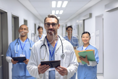 Medical team of doctors looking at camera in corridor at hospital