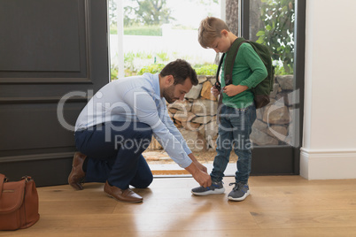 Father tying his sons shoelaces in a comfortable home