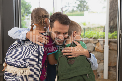 Father embracing his children at door in a comfortable home