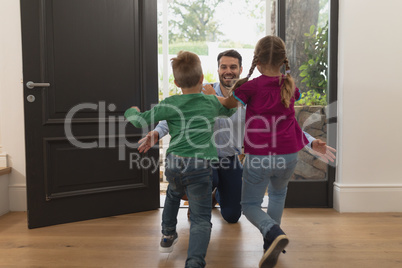 Children running towards father as he enters the house