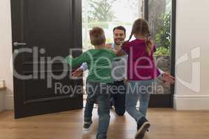 Children running towards father as he enters the house