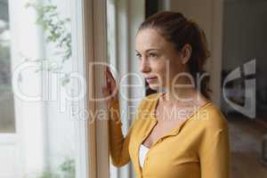 Woman looking outside through window in a comfortable home