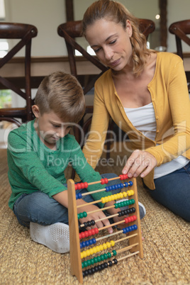 Mother teaching her son mathematics with abacus in a comfortable home