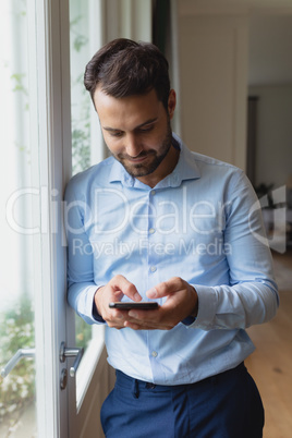 Man using mobile phone near window in a comfortable home