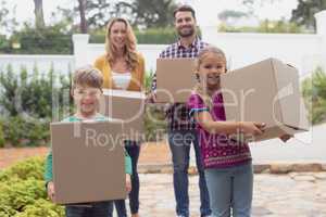 Happy Caucasian family holding cardboard boxes in home yard
