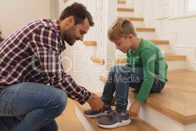 Father tying his sons shoelaces in a comfortable home