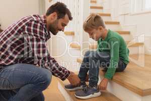 Father tying his sons shoelaces in a comfortable home