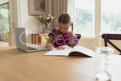 Cute girl doing homework at dining table in a comfortable home