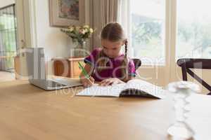 Cute girl doing homework at dining table in a comfortable home