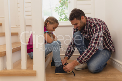 Father tying his daughter shoelaces in a comfortable home