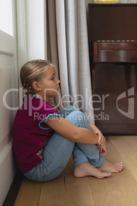Sad girl sitting alone in corner at home