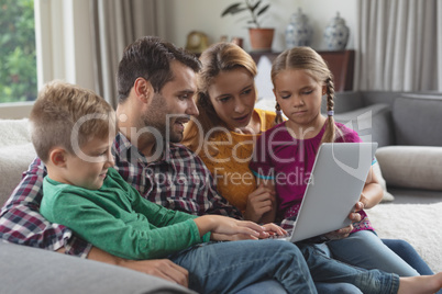 Caucasian family using laptop on the sofa in a comfortable home