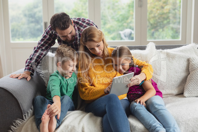 Caucasian family using digital tablet on the sofa in a comfortable home