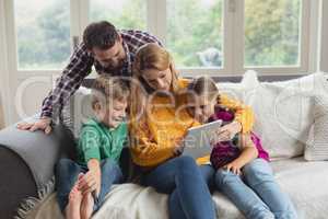 Caucasian family using digital tablet on the sofa in a comfortable home