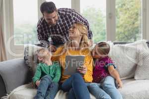 Family using digital tablet on the sofa in a comfortable home