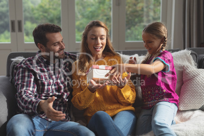 Daughter giving a gift to her mother in living room in a comfortable home