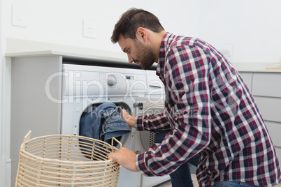 Man putting dirty clothes into the washing machine in a comfortable home