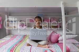 Girl using laptop on bed in a comfortable home