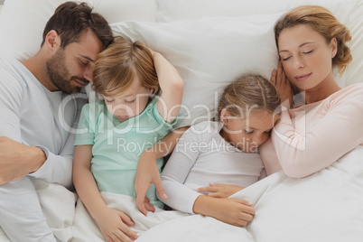 Caucasian family sleeping together in bed