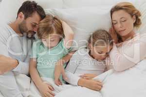 Caucasian family sleeping together in bed